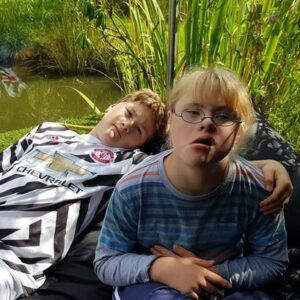 2 teenage brothers, 1 with down syndrome sitting together outside