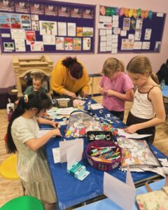 Fun club 2023 shows 4 children and 1 adult stood round a table participating in a craft activity